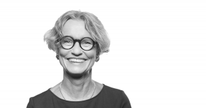 A female psychologist wearing glasses and smiling.