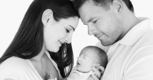 Two parents cuddle a newborn baby.